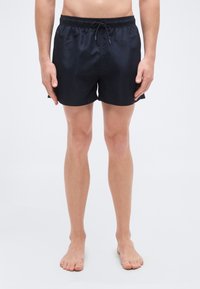 Μπλε ναυτικό μαγιό σορτς από ελαφρύ ύφασμα που στεγνώνει γρήγορα. Διαθέτει ελαστική μέση με κορδόνι, πλαϊνές σκισμές και ομαλή υφή.