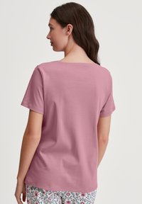 Roze T-shirt met korte mouwen en een ronde hals, gemaakt van zachte katoen. De achterkant is effen, met een gladde textuur en subtiele stikdetails.