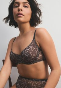 Set di reggiseno e mutande a vita alta in tessuto trasparente con stampa animalier, caratterizzato da spalline e cuciture nere, con una texture liscia e un design aderente.