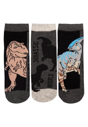 Tre calzini con disegni di dinosauri: un T-Rex marrone, silhouette nere con testo "Jurassic" e un Parasaurolophus a righe blu su sfondo scuro.