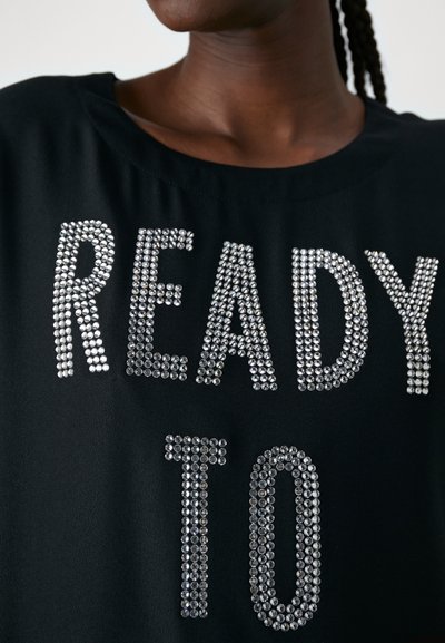 Juodas marškinėliai su sidabro spalvos deimantais sudarytu užrašu "READY TO". Turi apvalų iškirpimą ir minkštą, lygų audinio tekstūrą.
