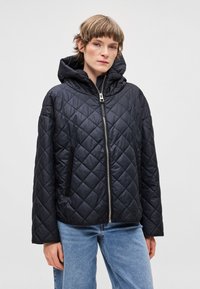 Čierna prešívaná bunda s kapucňou, vybavená predným zipsom, bočnými vreckami a voľným strihom. Hladká textúra a ľahký materiál.