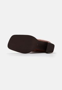 Chaussure en cuir marron avec une finition lisse, équipée d'une semelle noire plate et de motifs de texture subtils sur la surface supérieure. Taille 41 marquée en dessous.