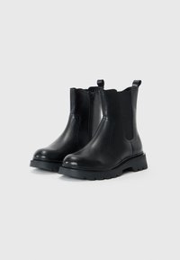 Bottines en cuir noir avec une finition lisse, fermeture éclair sur le côté, inserts élastiques, bout rond et semelle épaisse avec un motif de profondeur.