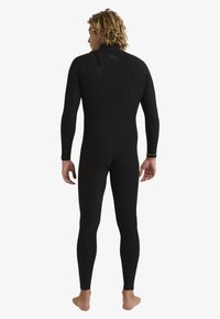 Black wetsuit made of stretchy material, featuring long sleeves, form-fitting design, and reinforced stitching. Back view shows smooth contours.