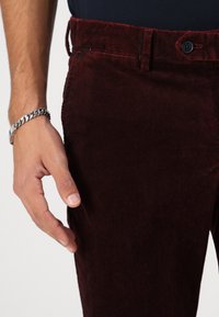 Bordo kordura hlače s teksturiranom površinom, klasičnim pojasom s gumbom i uskim krojem.