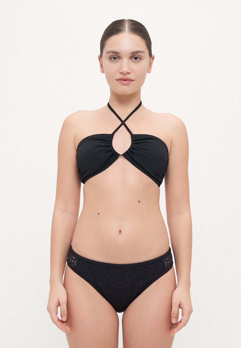 Črni bikini komplet z zgornjim delom na vezanje in ključavnico ter nastavljivimi naramnicami. Spodnji del ima zapleten vzorec izrezov.