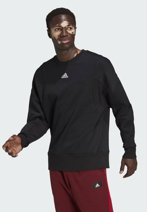 Schwarzes Sweatshirt mit Rundhalsausschnitt, langen Ärmeln und tailliertem Saum. Verfügt über subtile Paneldetails und ein kleines weißes Adidas-Logo auf der Brust.