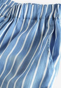 Blauw gestreepte stof met een zachte textuur, voorzien van witte verticale strepen en een elastische tailleband. Licht gedrapeerde uitstraling.