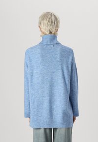 Pull en tricot bleu clair avec un col montant et des manches longues. Présente une coupe décontractée et un ourlet côtelé, fabriqué dans un tissu doux et texturé.