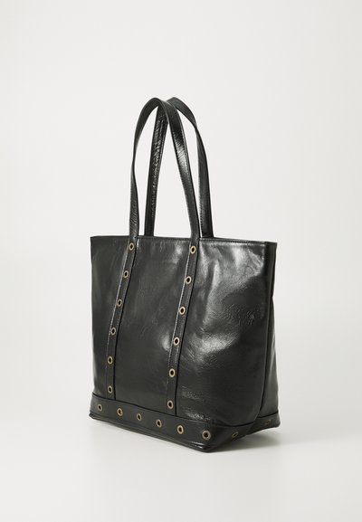 Sac fourre-tout noir en cuir avec double bandoulière et détails en œillets métalliques sur le devant et les bords inférieurs.