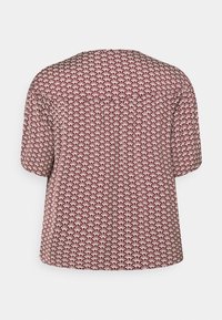 Short-sleeve top in burgundy with a cream leaf pattern. Loose fit, round neckline, and subtle gathering at shoulders. Soft fabric texture.