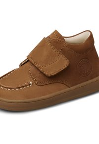Brun mockaskinnssko med rundad tå, justerbar kardborrerem, kontrasterande sömmar och gummisula. Har en präglad logotyp på sidan.