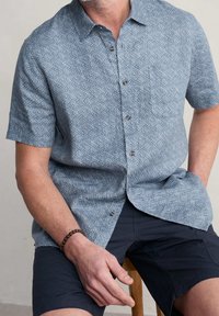 Korte mouw knoopshirt in lichtblauw met een geometrisch wit patroon, voorzien van een borstzak en een zachte stofstructuur.