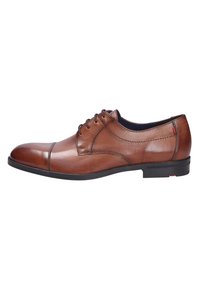 Scarpa da uomo in pelle marrone, con punta tonda, lacci e dettagli di cucitura sottili, caratterizzata da una suola in gomma nera e un accento rosso.