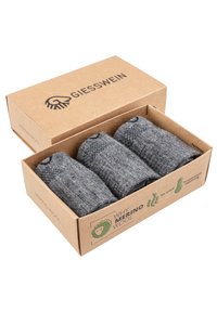 Graue Merinowollsocken ordentlich gerollt und verpackt in einer braunen Pappschachtel mit dem Markenlogo und Produktvorteilen, die an der Seite aufgedruckt sind.