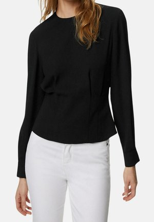 Czarna bluzka z długim rękawem o prostym kroju, z okrągłym dekoltem i gładką fakturą, zestawiona z białymi spodniami dla kontrastu.