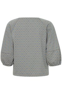 Blouse bleue à motifs avec un design géométrique en diamants beige. Elle a un col rond et des manches bouffantes, fabriquée dans un tissu texturé.