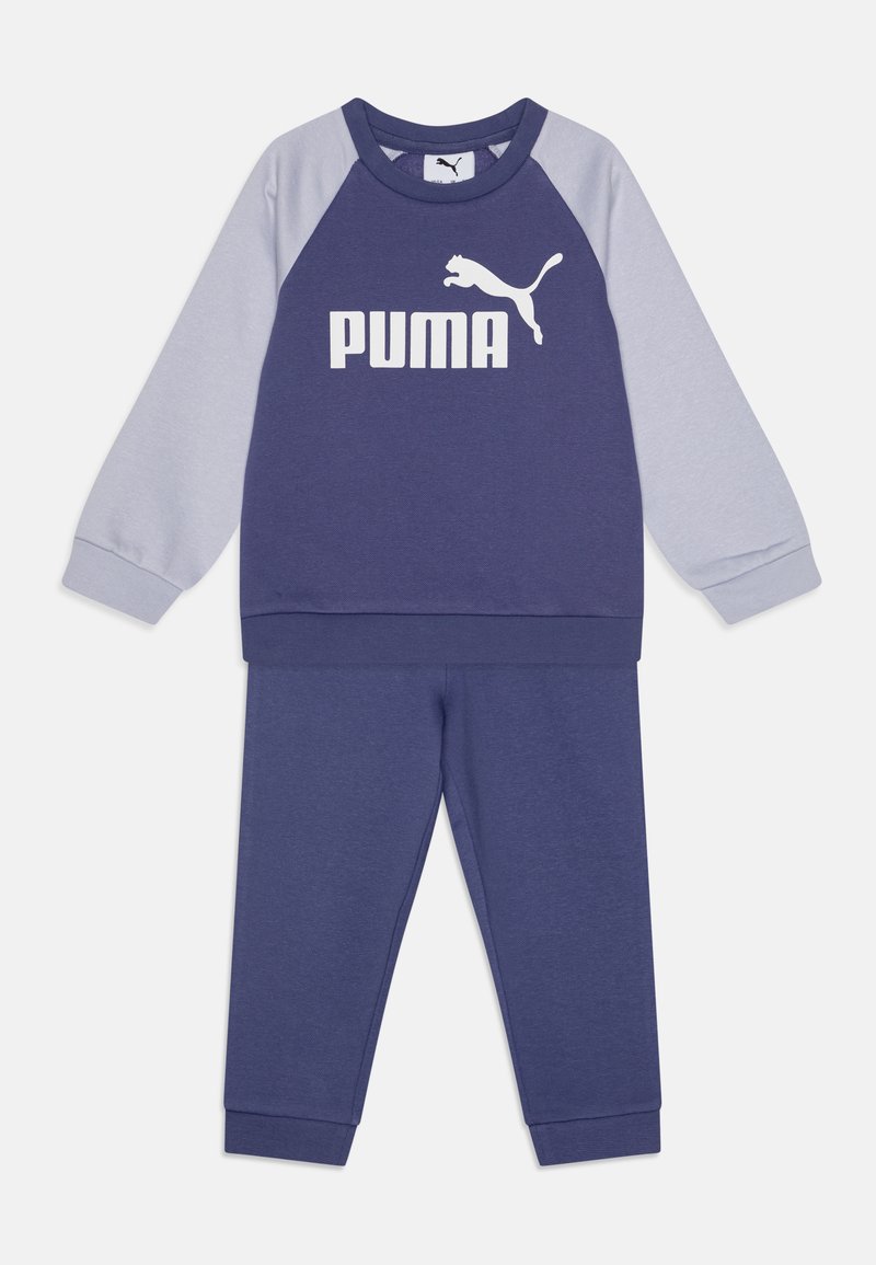 Mörkblå och ljusgrå sweatshirt med långa raglanärmar, med en stor vit "PUMA"-logotyp på framsidan, i kombination med matchande byxor.