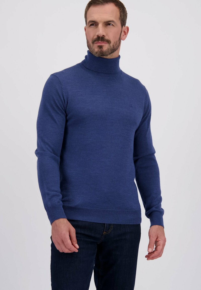 Pull à col roulé bleu marine en tissu doux, à coupe ajustée, avec des poignets et un ourlet côtelés, porté avec un jean foncé.