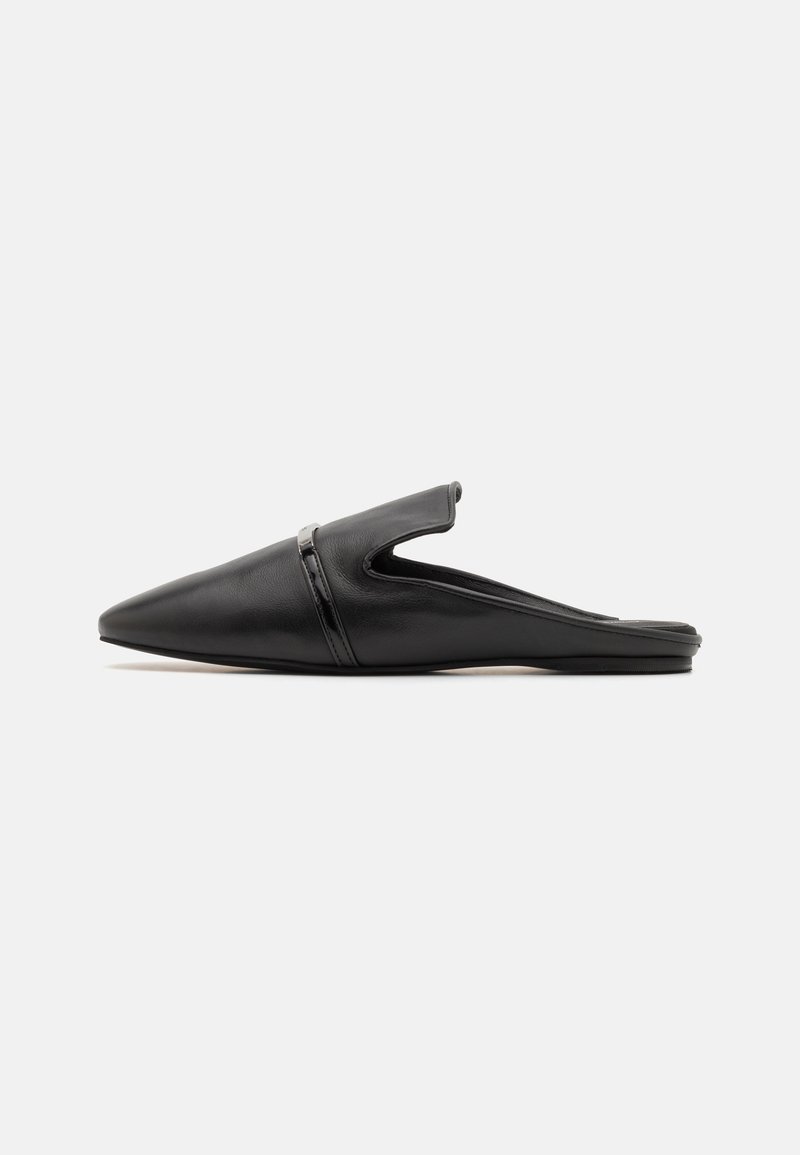 Mule en cuir noir à bout pointu, sans lacets, avec un petit talon plat et une bride décorative sur le dessus.
