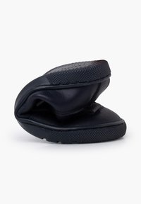 Zapatos negros de piel tipo slip-on, textura suave, forma redondeada, diseño flexible, con suela de goma que presenta un agarre texturizado para mayor estabilidad.