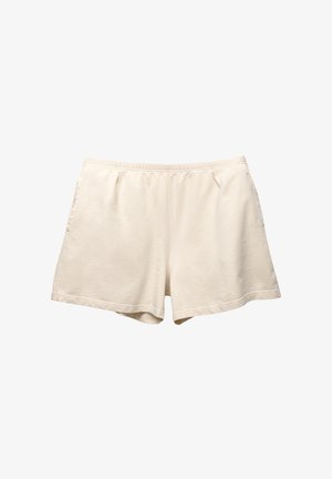 Shorts en coton beige clair avec une taille élastique, deux poches latérales et une coupe décontractée. Texture lisse avec un design simple et sans ornement.