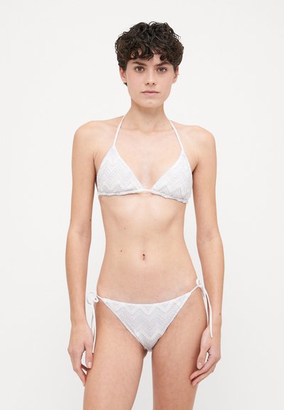 Hvid bikini med zigzag-mønster, trekantet top med tynde stropper og lavtaljede bunddele med justerbare snore i siderne.