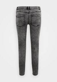 Jeans skinny de denim negro con una textura suave, que cuentan con dos bolsillos traseros y una cintura clásica. La tela muestra un sutil patrón desgastado.