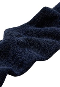 Mørk marineblå håndklæde med en struktureret overflade, der har bløde, luksuriøse fibre og en bølget kant, velegnet til forskellige formål.