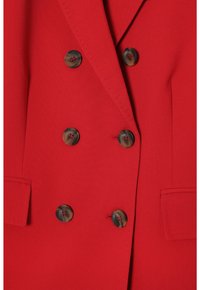 Červený dvouřadý blazer s hladkým povrchem, se tmavými knoflíky s mramorovým vzorem a dvěma bočními kapsami.