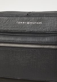 Schwarze, strukturierte Kosmetiktasche mit einem silbernen Reißverschluss und Logo. Verfügt über eine rechteckige Form und ein strapazierfähiges, synthetisches Leder-Material.