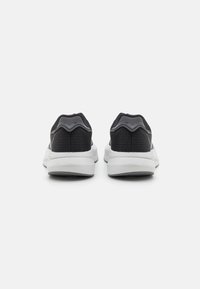 Schwarze Textilsneaker mit grauen Akzenten und einer weißen Sohle, ausgestattet mit einem runden Absatz und einem strukturierten Obermaterial für Atmungsaktivität.
