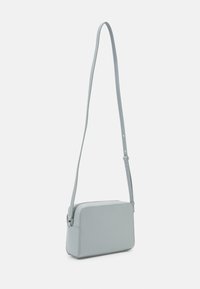 Borsa a tracolla azzurra chiara realizzata in materiale liscio, forma rettangolare, cinturino regolabile sottile e chiusura a zip. Design minimalista, senza motivi visibili.