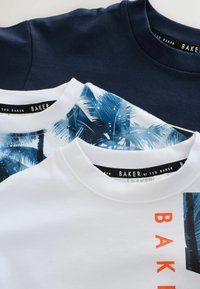 Trois t-shirts en coton : bleu marine, blanc, et un avec un imprimé de palmier bleu. Chacun a un col rond et affiche le logo de la marque « BAKER ».