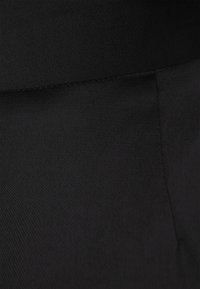 Zwarte stof, gladde textuur, nauwsluitend ontwerp. Heeft een hoge tailleband met subtiele stiksels en geen zichtbare patronen of hardware.