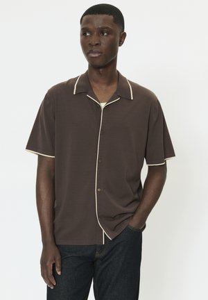 Braunes Kurzarmhemd mit kontrastierendem beigem Kragen und Knopfleiste, in lässiger Passform und strukturierter Stoffstruktur, kombiniert mit dunklen Jeans.