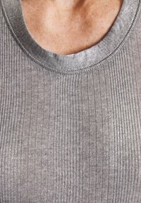 Top gris con textura acanalada y un escote amplio, con un brillo metálico. Presenta una textura suave y costuras en contraste a lo largo de los bordes.