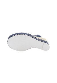 Bílá gumová podrážka s texturovaným povrchem, horní část z tmavě modré textilie a kontrastní šití podél okraje, plochý design.