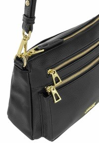 Czarna skórzana torebka na ramię z fakturowanym wykończeniem, wyposażona w podwójne złote suwaki oraz odpinany pasek z akcentami w kolorze złota.