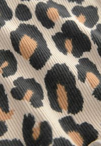 Tessuto testurizzato con uno sfondo crema e grandi macchie di leopardo nere e beige. Il motivo è predominante con una texture a righe.