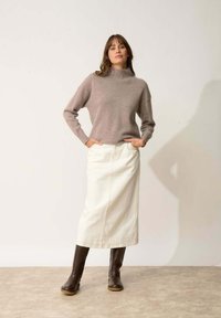 Jasnobrązowy sweter z dzianiny o wysokim kołnierzu, zestawiony z białą spódnicą dżinsową i brązowymi skórzanymi botkami do kolan. Prosty wzór, neutralne kolory.