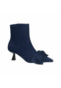 Bottes chelsea en tissu bleu marine avec un bout pointu, un petit talon noir et un détail de nœud noué sur le côté. Texture lisse.
