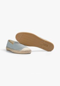 Lichtblauwe espadrilles met een natuurlijke jute touwzool, beige canvas neuskap en gekleurde rubberen loopzool. Minimalistisch instapontwerp.