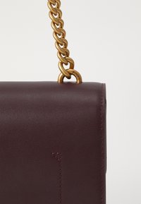 Μπορντό δερμάτινη τσάντα με χρυσό λουρί αλυσίδας, με κομψό, ορθογώνιο σχήμα και διακριτές ραφές.