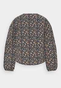 Blouse marine à fleurs avec manches longues bouffantes, ornée de petites fleurs orange et bleues sur un tissu texturé. Encolure arrondie et coupe courte.