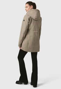 Bēšas vidēja garuma jaka ar kapuci, garām piedurknēm un sašaurinātu jostasvietu. Tās struktūra ir gluda, un piedurknei ir smalka dizaina detaļa.