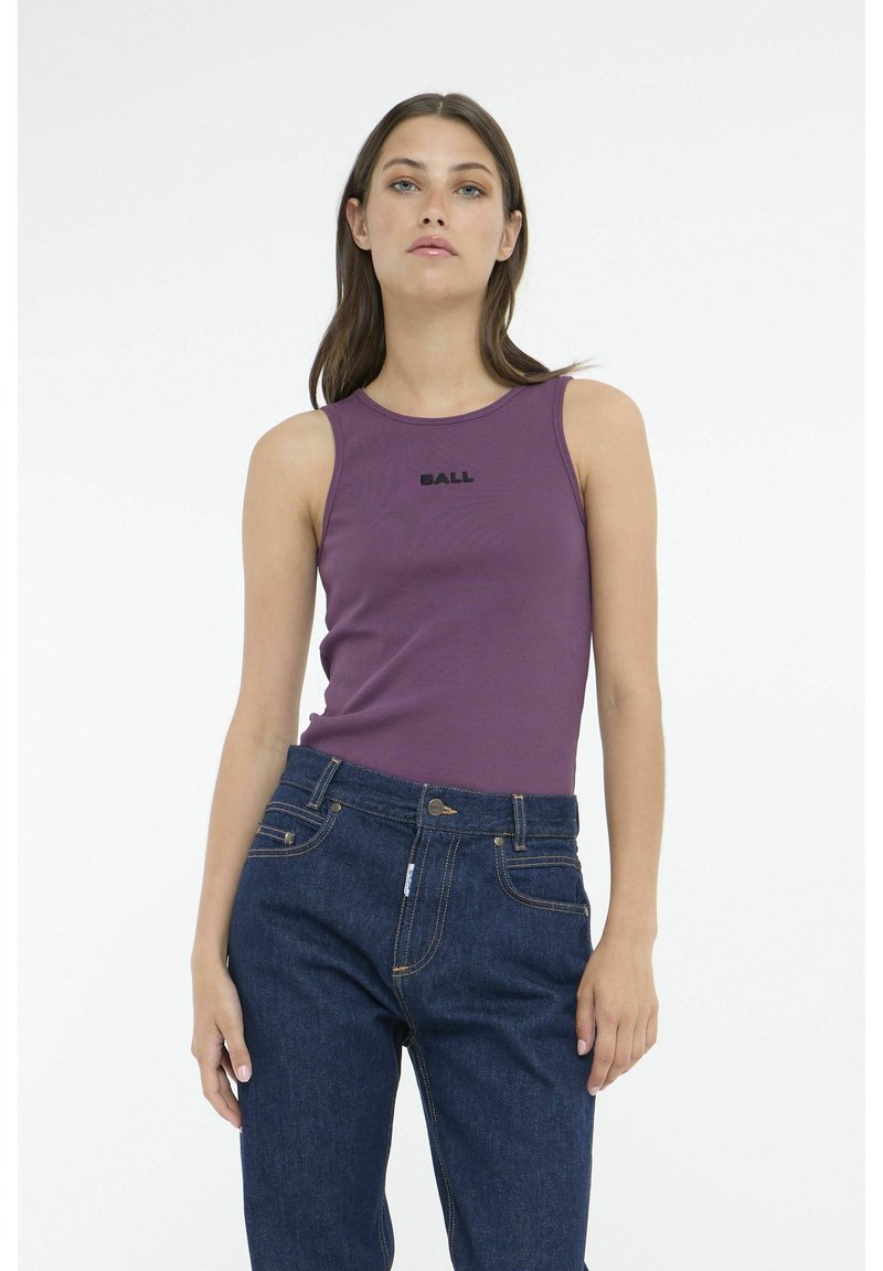 Top a canotta viola con texture a costine e la scritta "BALL" nera, abbinata a jeans blu scuro con dettagli di cucitura e finitura in denim.