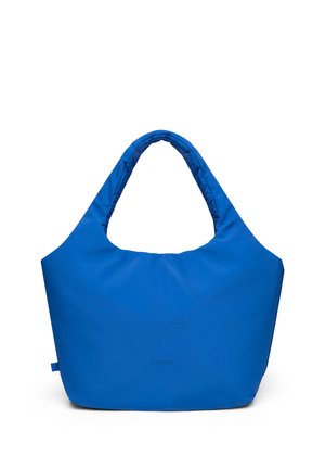 Geantă de pânză moale albastră, cu mânere căptușite și logo minimalist în partea din față, stând vertical pe un fundal alb.