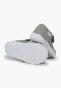 Scarpe in tela grigia con suola in gomma bianca, dotate di una fascia in Velcro e dettaglio testurizzato sul retro. Top paesaggistico colorato sul lato.